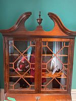 Front view of the wood secretary desk showing glass cabinet doors with decorative wood grid design.