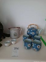 Photo showing two tea pots and six tea cups arranged together with visible bamboo handles on tea pots and matching designs.