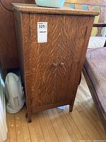 Front view of the oak wood cabinet showing two doors with round wooden knobs and natural wood grain finish.