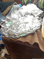 Overview of multiple antique crystal glasses arranged on the large silver-plated tray on a textured cloth surface.