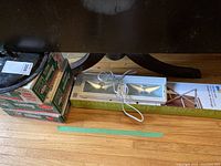 Photo showing three boxes of 250 ml canning jars with lids, under counter light fixture with power cord laid on floor under table.