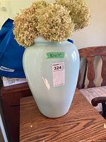 Front view of pale green ceramic vase with dried flowers inside, showing size sticker and lot sticker.