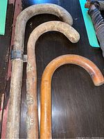 Three vintage wooden walking canes displayed on a table, showing different wood tones and curved handles.