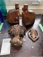 Pair of carved wooden turtle bookends and two wood finials, one pineapple shaped and one leaf shaped, shown from top and front angles.