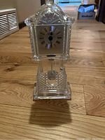 Front view of the crystal mantel clock showing the clock face with Roman numerals and textured crystal case.