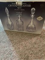 Box showing the three crystal decanters, highlighting 24% lead crystal and detailed cut patterns.