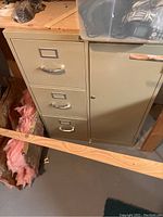 Closed view of beige metal file cabinet with three drawers and a lockable compartment door.