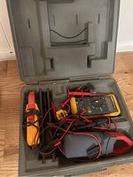 Open hard plastic carrying case containing Fluke 73III multimeter, test leads, probes, and clamp meter accessory