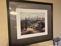 Framed limited edition landscape print with mountains, hills, and fireweed flowers, showing overall view of item on wall.