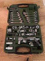 Green carrying case open, showing ratchet handles, various socket sizes, combination wrenches, bits, and extensions in designated molded spots.