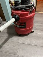 Photo of red Craftsman 10 gallon wet/dry shop vacuum with black top and no hose, placed on wood floor.