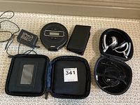 Overview photo showing all items in the lot including the cassette player, adapter, carrying case, and Bluetooth headset with case.