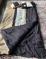 Full view of comforter laid out showing the color block pattern with beige, black, and cream sections and quilted texture.