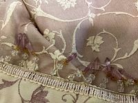 Close-up of beadwork detail on edge of tablecloth showing purple, clear, and gold beads.