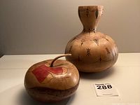 Two unique gourd art pieces side by side, showing the large rounded double-bulb gourd and the apple-shaped gourd with red painted decoration and carved stem.