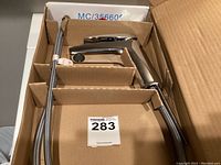 Boxed pullout kitchen faucet with chrome finish and flexible braided hose, ergonomic handle shown in cardboard packaging.