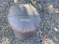 Sleeping bag packed inside its black storage sack labeled with Mountain Hardwear logo and model name Bozeman 5°F/-15°C REG.