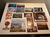 Photo showing an assortment of Soviet-themed postcards and booklets laid flat on a white table. Includes images of buildings, landscapes, Russian porcelain, and a booklet titled 'Welcome to Soviet Azerbaijan'.