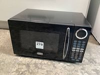 Front view of black Sunbeam microwave oven showing door, window, handle, and digital control panel with buttons and dial.