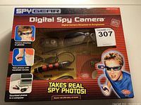 Front view of original unopened box showing the spy camera sunglasses visible inside, handheld remote, and colorful graphics with text.