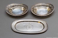 Top view showing two oval condiment bowls with floral borders and one butter dish with monogram