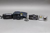 Four cameras arranged side by side on grey surface
