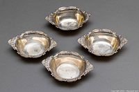 Four Birks sterling silver condiment bowls or salt cellars shown from top, arranged in square formation to display interiors and ornate handles.