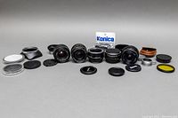 Wide shot showing all items including multiple camera lenses, adapters, lens caps, and accessories laid out in a row.