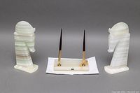 Pair of carved Mexican onyx horse head bookends flanking an onyx pen holder base with two pens, shown on white paper towel against gray background.