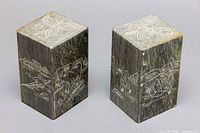 Pair of rectangular soapstone bookends featuring detailed Inuit wildlife and cultural etchings on all visible sides including tops.