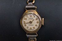Front view of the vintage LANCO watch face showing dial, gold Arabic numerals and hands, and gold-plated casing with wear.