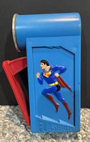 Front view of the blue flashlight with Superman figure in raised decore and red handle folded in.
