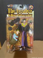 Front view of The Beatles Yellow Submarine John Lennon figure sealed in original packaging with Jeremy accessory visible.