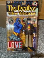 Front view of sealed Paul McCartney action figure from Beatles Yellow Submarine series with 'LOVE' hand accessory in original packaging