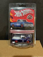 Front view of unopened blister package containing dark blue 1962 Ford F100 truck with red wheels, Hot Wheels Red Line Club branding visible.