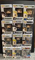 Photo of 12 boxed Funko Pop figures from Fallout theme displayed in rows showing front of boxes and characters inside.