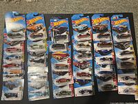 Lot of 31 Hot Wheels die-cast cars new in packaging arranged in rows on floor