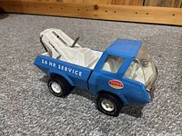 Side view of blue vintage Tonka tow truck showing 24 Hr Service decal and tow arm details.