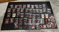 Over 49 vintage WWF Hostess stickers laid out on black surface, individually sleeved in plastic protectors, showing different wrestlers.