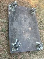 Top view of the wooden base with four metal swivel caster wheels, placed upside down on the grass.