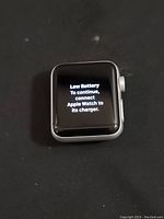 Front display of Apple Watch showing low battery message on screen indicating it powers on and has display functional.