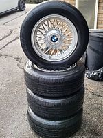 Stack of four silver multi-spoke BMW alloy rims mounted with Michelin tires showing wheel design and center caps