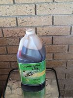 1-gallon plastic container of all season chain saw oil with green label and handle, suitable for lubricating chainsaw chains.