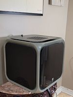Front and side angled view showing black tempered glass panels framed in silver on the cube-shaped kitchen hood. Top vent visible.