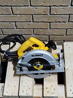 Dewalt 7 1/4 inch circular saw placed on a wooden pallet showing the full tool including blade, handle and power cord.