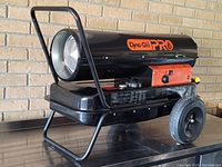Side angle view of the Dyna-Glo Pro forced air heater showing cylindrical black body, large wheels, and handle.