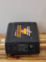Front view of the black Eliminator 2000 watt digital power inverter showing top branding and front panel ports including AC outlets and cooling fan.