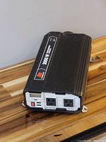 Photo of black Eliminator 2000 watt power inverter showing dual AC outlets, power switch, and labeling.