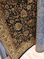 Angled view showing black field with floral pattern and beige border