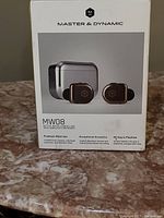 Photo of the product box showing branding, model number MW08, features such as active noise cancelling, 40 hours playtime, and premium materials.